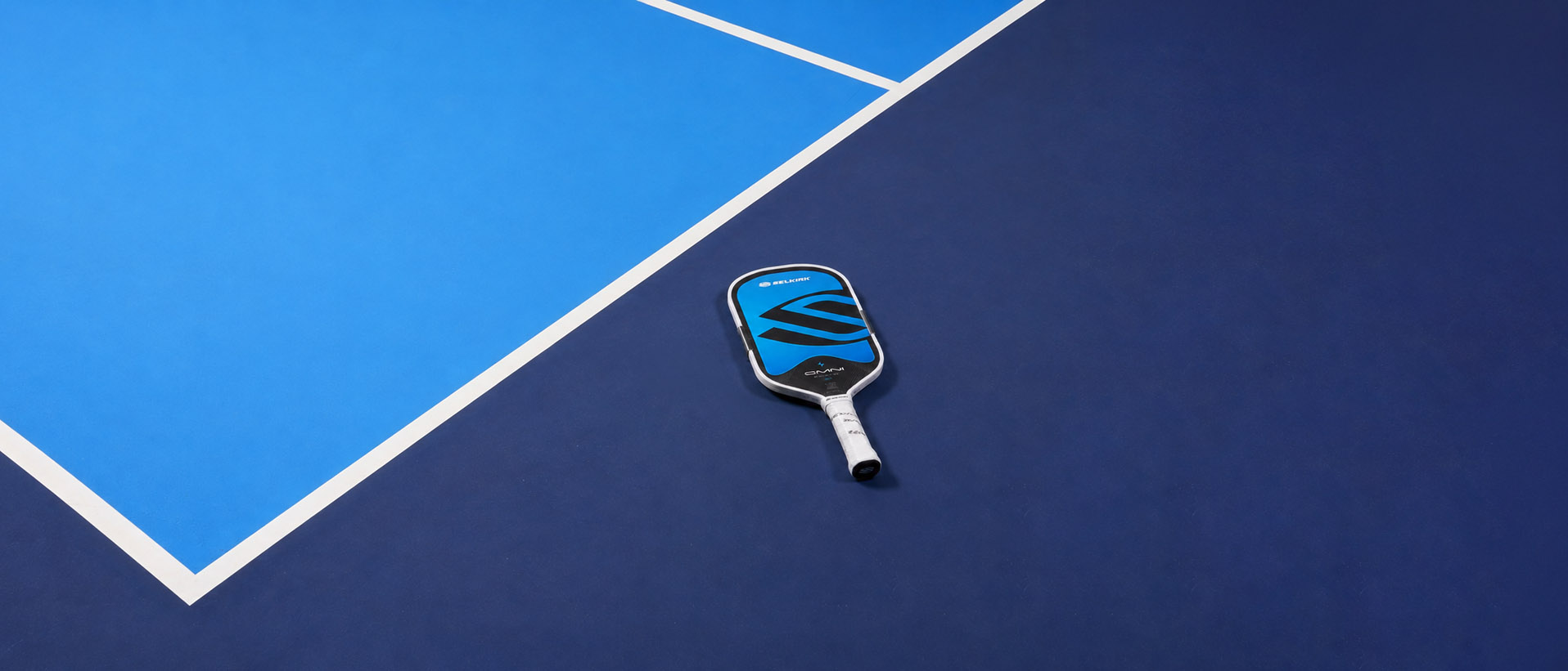 A pickleball paddle resting on the blue and navy surface of a court